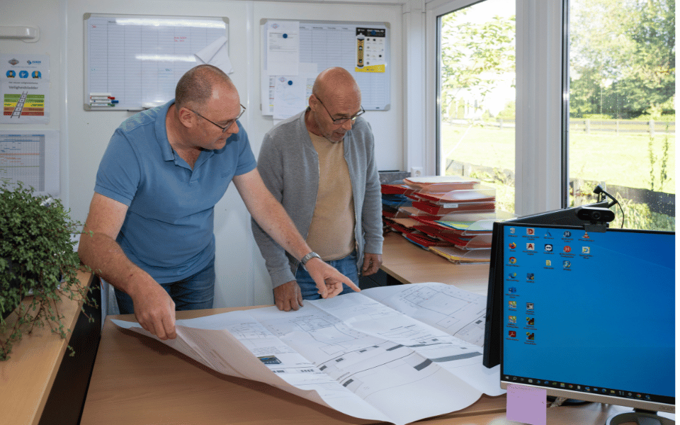 Twee medewerkers van Agado Van Gameren bespreken een bouwtekening op kantoor